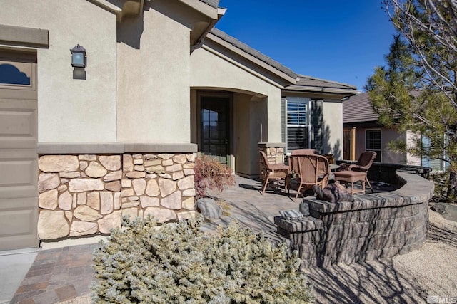 exterior space with stone siding, a patio, and stucco siding