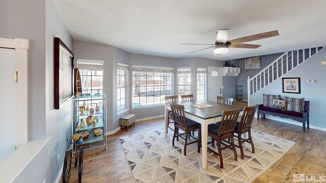 dining space featuring a ceiling fan, stairway, light wood-style flooring, and baseboards