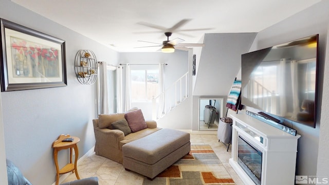 living room featuring ceiling fan, light tile patterned floors, and stairway