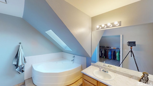 full bath with a bath, vaulted ceiling with skylight, and vanity