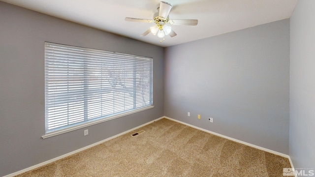 spare room featuring a ceiling fan, carpet flooring, visible vents, and baseboards