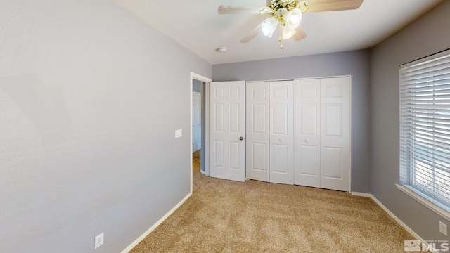 unfurnished bedroom with a ceiling fan, a closet, light colored carpet, and baseboards