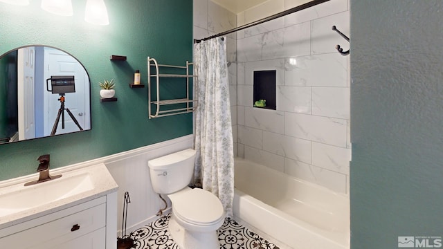 bathroom featuring a wainscoted wall, a textured wall, shower / bathtub combination with curtain, toilet, and vanity