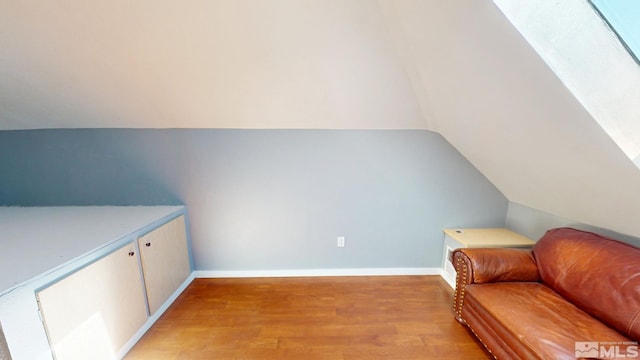 sitting room featuring light wood-type flooring, baseboards, and lofted ceiling