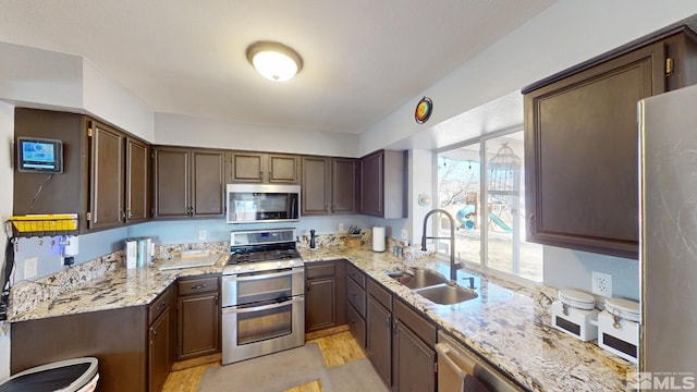 kitchen featuring stainless steel appliances, a sink, and light stone countertops