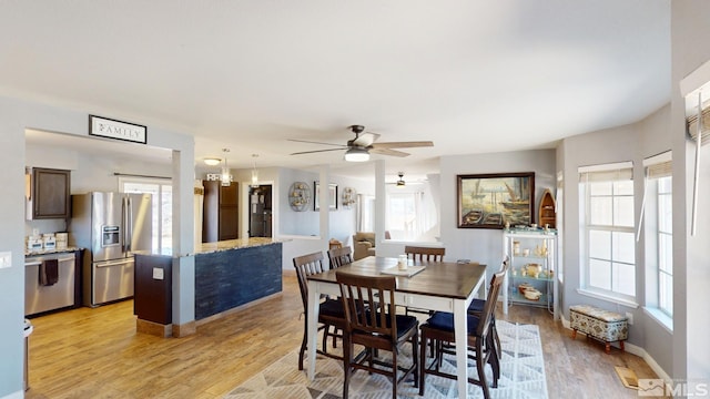 dining room featuring light wood finished floors, baseboards, and a ceiling fan