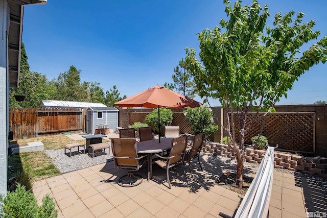 view of patio with an outbuilding, a shed, outdoor dining area, and a fenced backyard