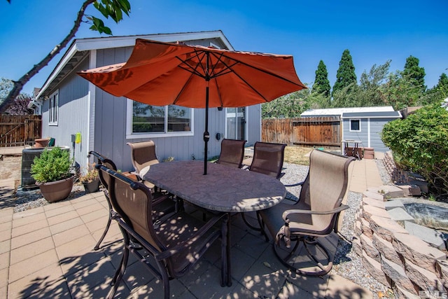 view of patio with outdoor dining space, an outdoor structure, a fenced backyard, and cooling unit