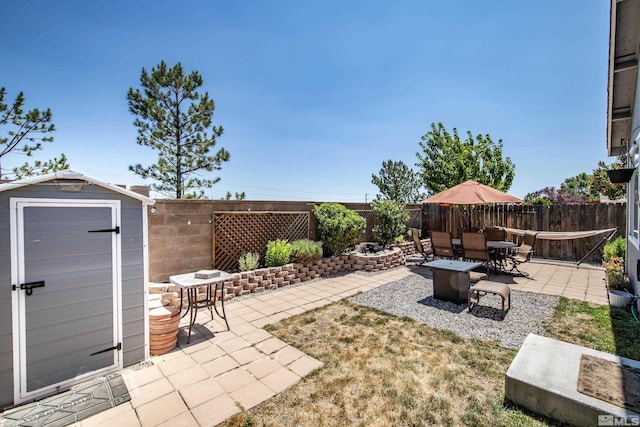 view of patio / terrace featuring outdoor dining space, a fenced backyard, an outdoor structure, and a storage unit