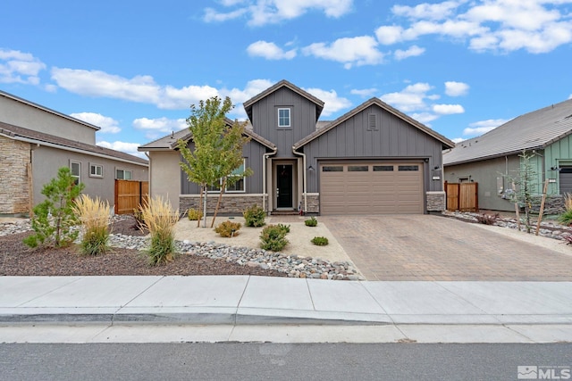 view of front of home featuring stone siding, decorative driveway, an attached garage, and fence