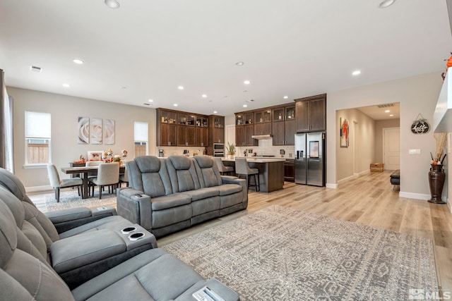 living area with plenty of natural light, light wood-style flooring, baseboards, and recessed lighting