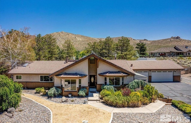 view of front of home with driveway, a tiled roof, an attached garage, a mountain view, and stucco siding