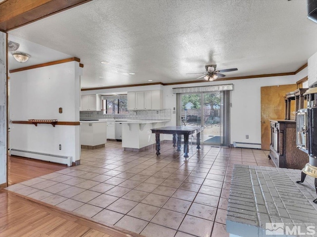 kitchen featuring ornamental molding, a peninsula, tasteful backsplash, and baseboard heating