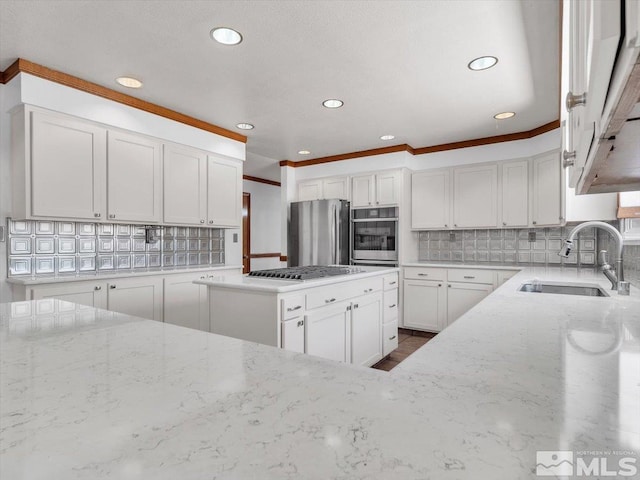 kitchen with light stone countertops, stainless steel appliances, a sink, white cabinets, and decorative backsplash