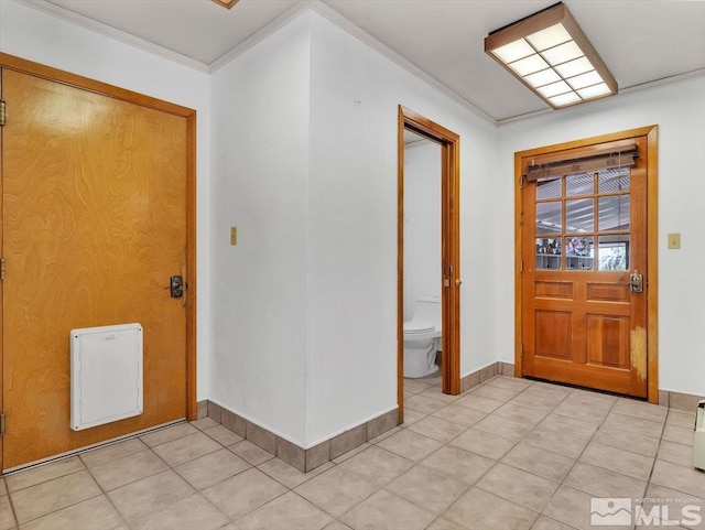 foyer entrance with light tile patterned flooring, crown molding, and baseboards