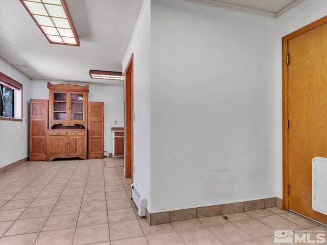 hallway featuring ornamental molding, baseboards, baseboard heating, and light tile patterned floors