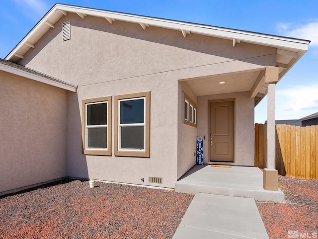 property entrance with fence and stucco siding