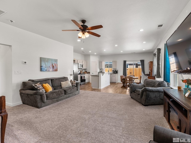 living room with visible vents, baseboards, light colored carpet, ceiling fan, and recessed lighting