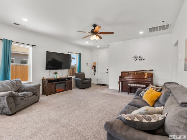 living area with recessed lighting, visible vents, a glass covered fireplace, and carpet flooring