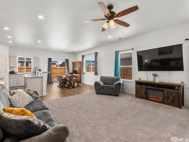 living room featuring recessed lighting, visible vents, baseboards, a ceiling fan, and a glass covered fireplace