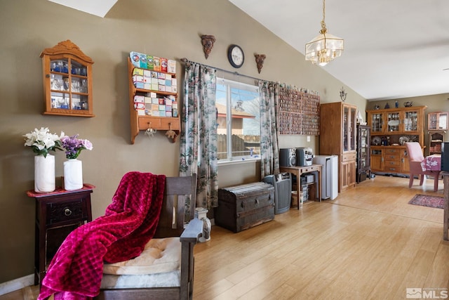 sitting room with vaulted ceiling, wood finished floors, and an inviting chandelier