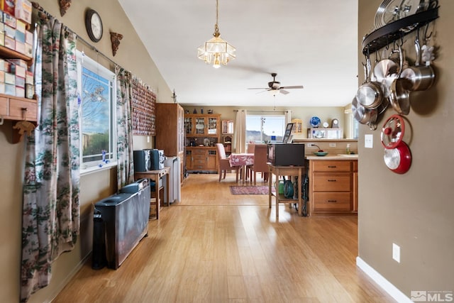 interior space featuring vaulted ceiling, light wood finished floors, a ceiling fan, and baseboards