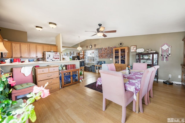 dining space with ceiling fan, light wood-style flooring, baseboards, and vaulted ceiling