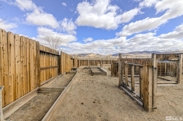 view of yard with a garden, fence, and a mountain view