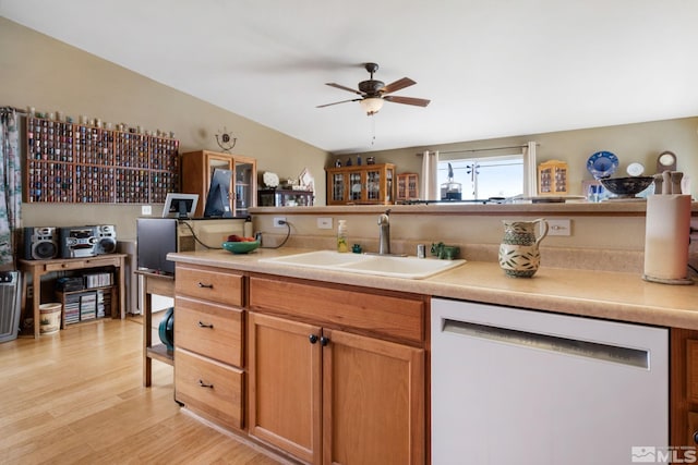 kitchen featuring a ceiling fan, dishwasher, light countertops, light wood-style floors, and a sink