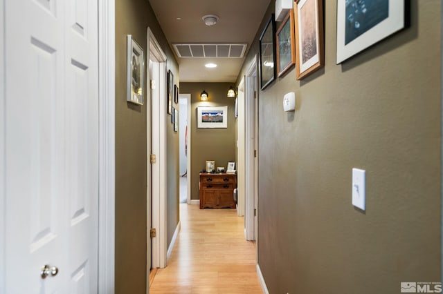 hall featuring light wood-type flooring, visible vents, and baseboards