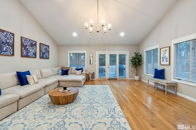 living area featuring a chandelier, high vaulted ceiling, wood finished floors, baseboards, and french doors