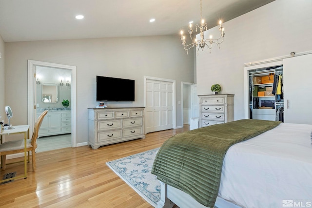 bedroom with two closets, recessed lighting, light wood-style floors, connected bathroom, and a chandelier