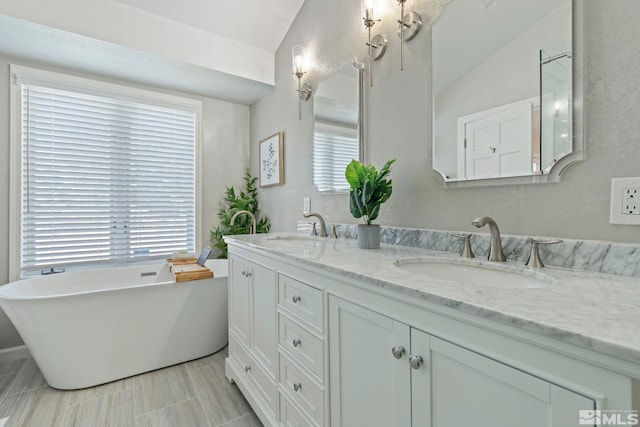 full bathroom with a freestanding bath, double vanity, and a sink