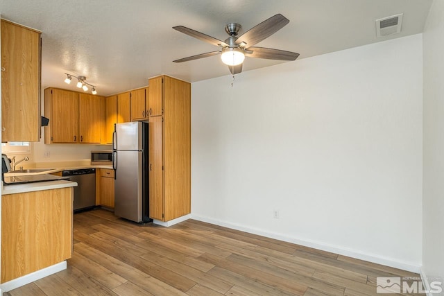 kitchen featuring light wood finished floors, visible vents, stainless steel appliances, light countertops, and a sink