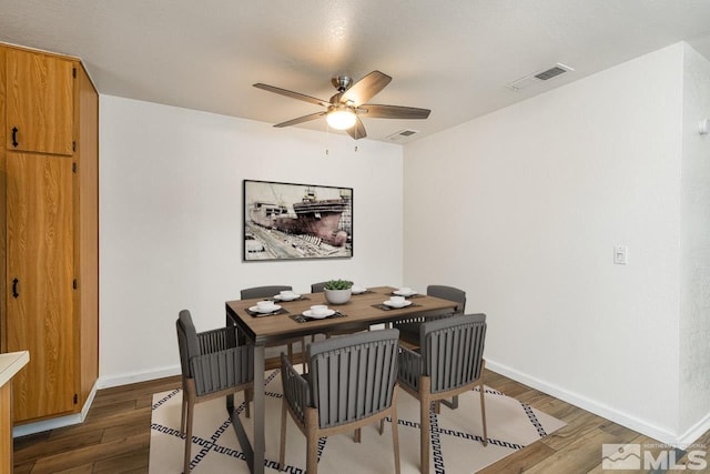 dining room featuring dark wood-type flooring, visible vents, ceiling fan, and baseboards