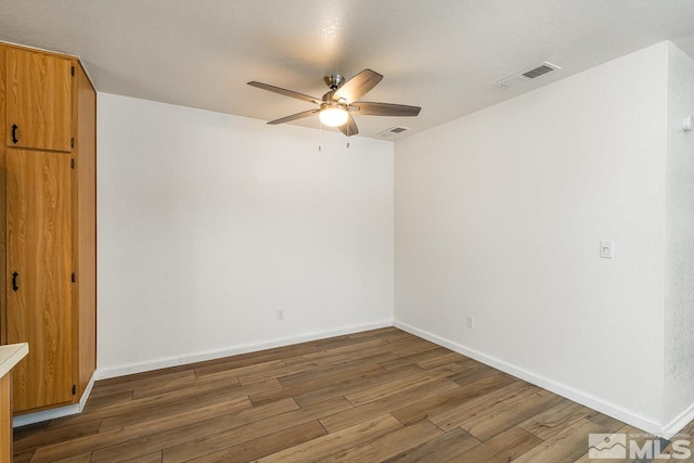 spare room with visible vents, ceiling fan, baseboards, and wood finished floors