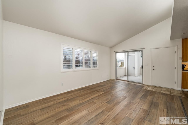 spare room with high vaulted ceiling, wood finished floors, and baseboards