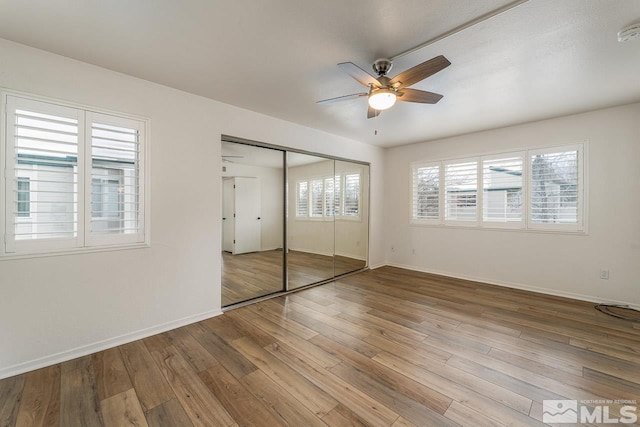 unfurnished bedroom with a closet, ceiling fan, baseboards, and wood finished floors