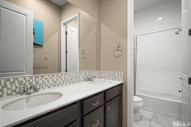 full bath featuring tasteful backsplash, a sink, toilet, and double vanity