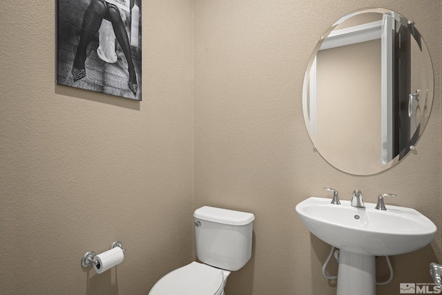 bathroom featuring a textured wall and toilet