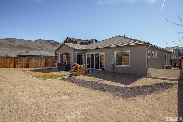 rear view of house with a patio area, fence, a mountain view, and stucco siding