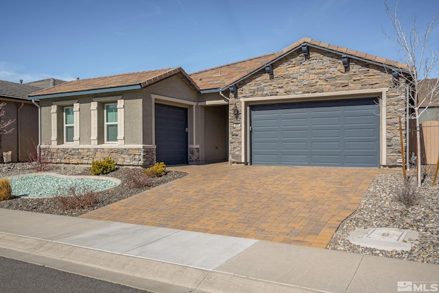 view of front facade featuring a garage, stone siding, a tiled roof, decorative driveway, and stucco siding