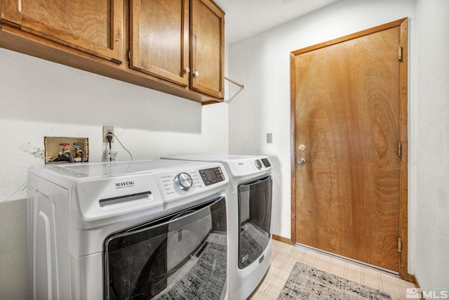 laundry room featuring light floors, washer and clothes dryer, and cabinet space