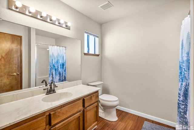 full bath with baseboards, visible vents, toilet, wood finished floors, and vanity