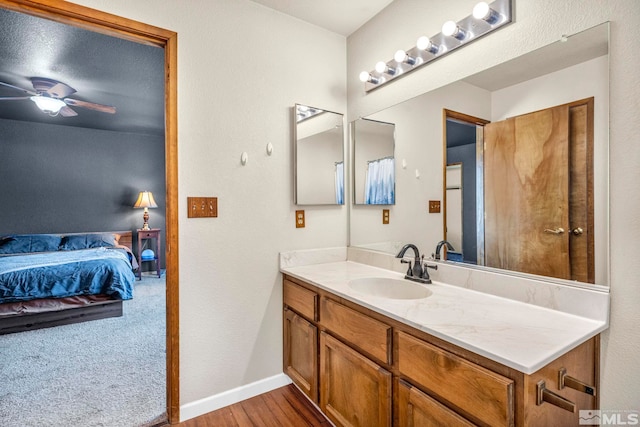 bathroom featuring connected bathroom, vanity, ceiling fan, wood finished floors, and baseboards