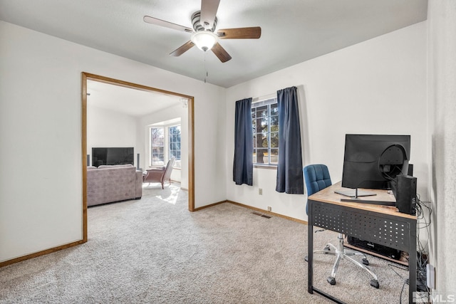 office space featuring carpet floors, a ceiling fan, visible vents, and baseboards