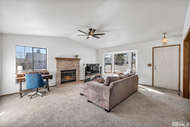 carpeted living area with a ceiling fan, vaulted ceiling, a fireplace, and plenty of natural light