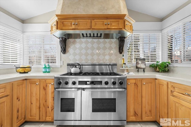 kitchen with range with two ovens, vaulted ceiling, tile countertops, and tasteful backsplash