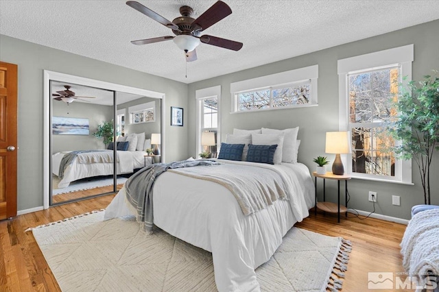 bedroom featuring a textured ceiling, a closet, wood finished floors, and a ceiling fan