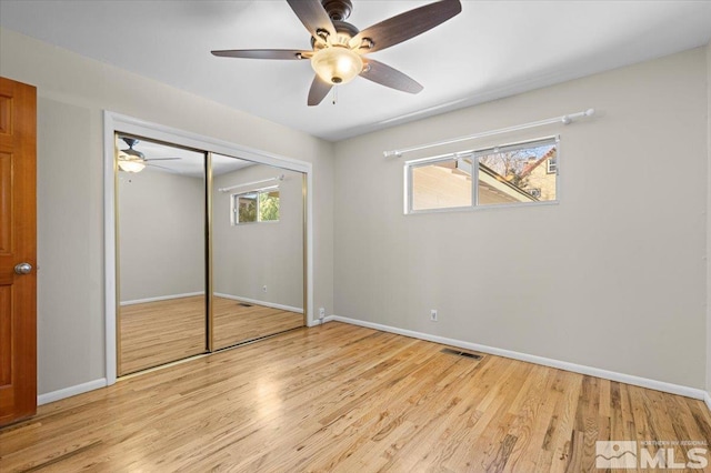 unfurnished bedroom featuring multiple windows, wood finished floors, and visible vents